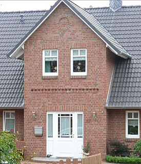 Hauseingang mit Erker aus rötlichem Verblender und weißer Haustür